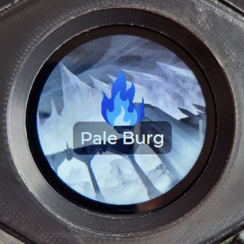 The circular display, embedded in its hex tile, showing the Pale Burg screen: an ethereal blue flame icon atop an imposing mountain and spiked bridge. The circular display, embedded in its hex tile, showing the Pale Burg screen: an ethereal blue flame icon atop an imposing mountain and spiked bridge.
