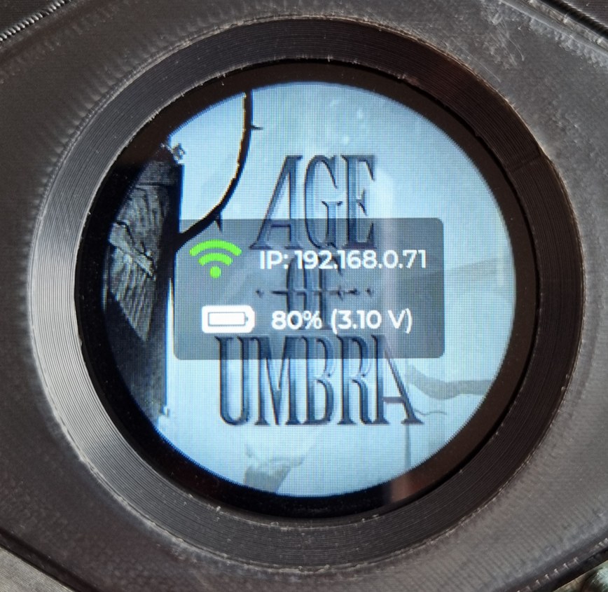 The circular display, embedded in its hex tile, showing the status screen. Overlay text shows WiFi connected at IP 192.168.0.71 and the battery at 80 percent (3.10V), rendered over the Age of Umbra logo. The circular display, embedded in its hex tile, showing the status screen. Overlay text shows WiFi connected at IP 192.168.0.71 and the battery at 80 percent (3.10V), rendered over the Age of Umbra logo.