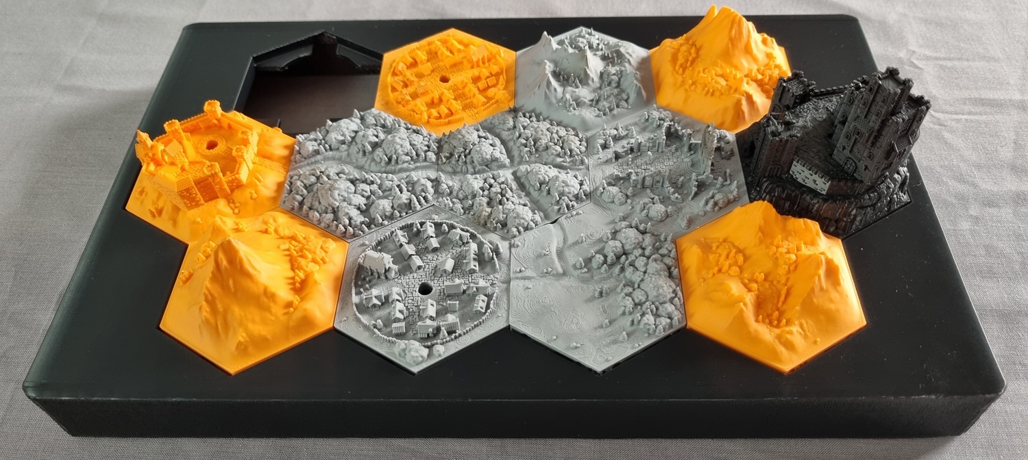 Test-fitting the final configuration of the (unpainted) Hexton Hills tile map in the main enclosure. The tiles are printed in a mix of orange and grey PLA, with the Pale Burg in black.