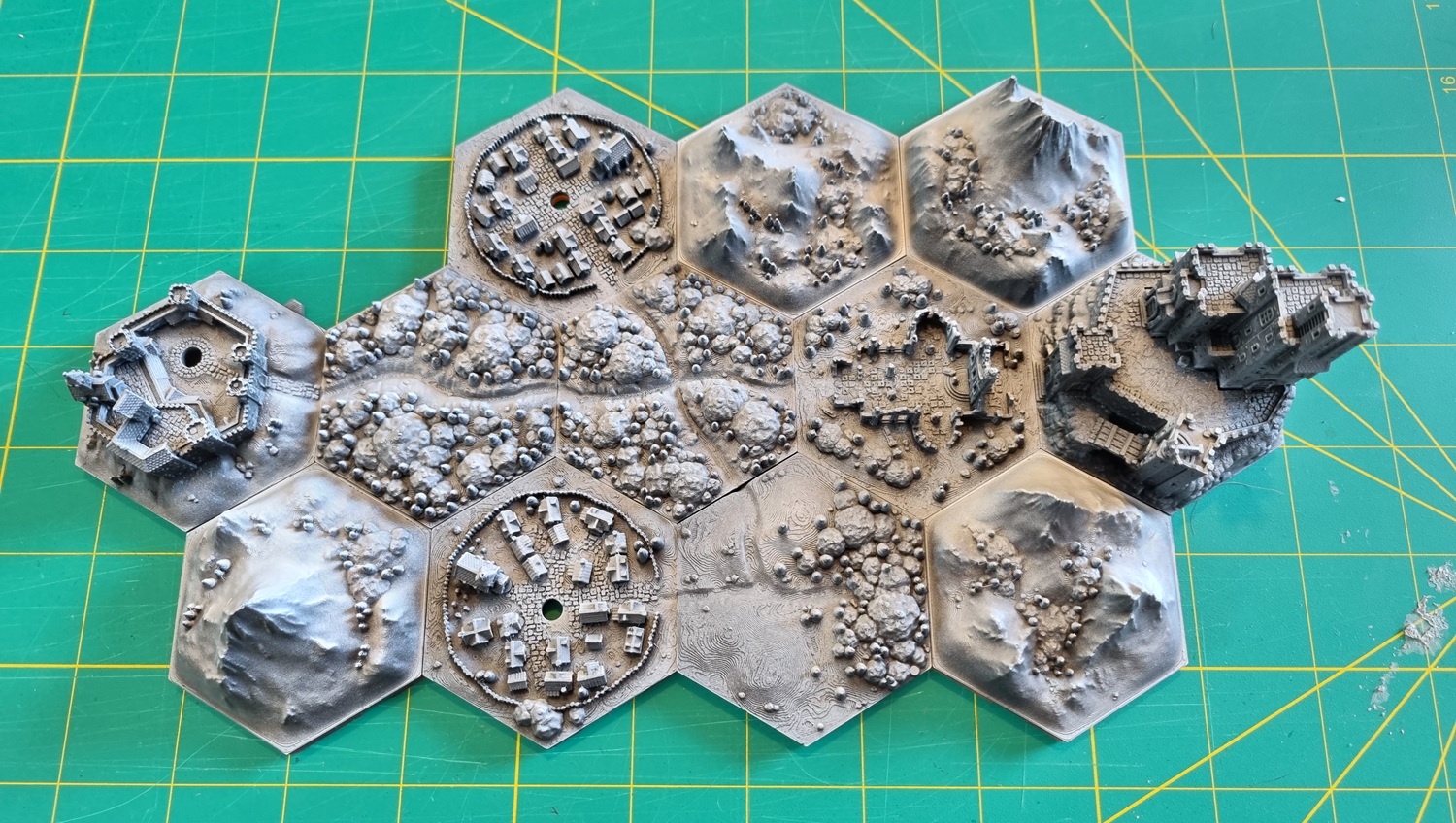 Top-down view of the zenithal basecoated hex tile map sitting on a cutting mat. Raised areas are bright white, recesses are dark shadow. Top-down view of the zenithal basecoated hex tile map sitting on a cutting mat. Raised areas are bright white, recesses are dark shadow.